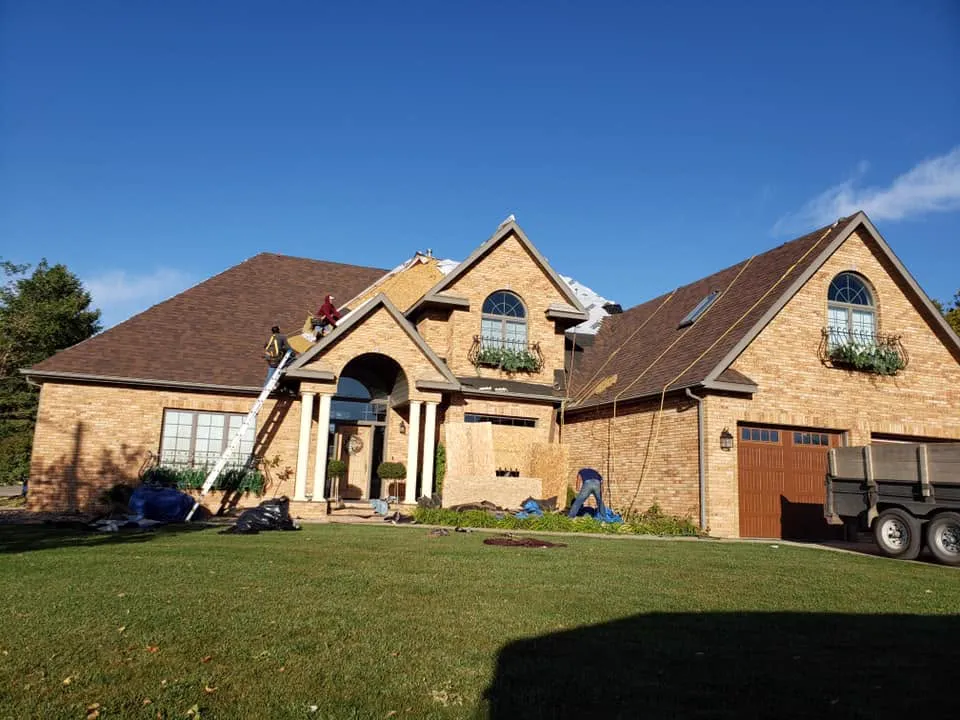 A crew replacing the roof on a large two-story brick home