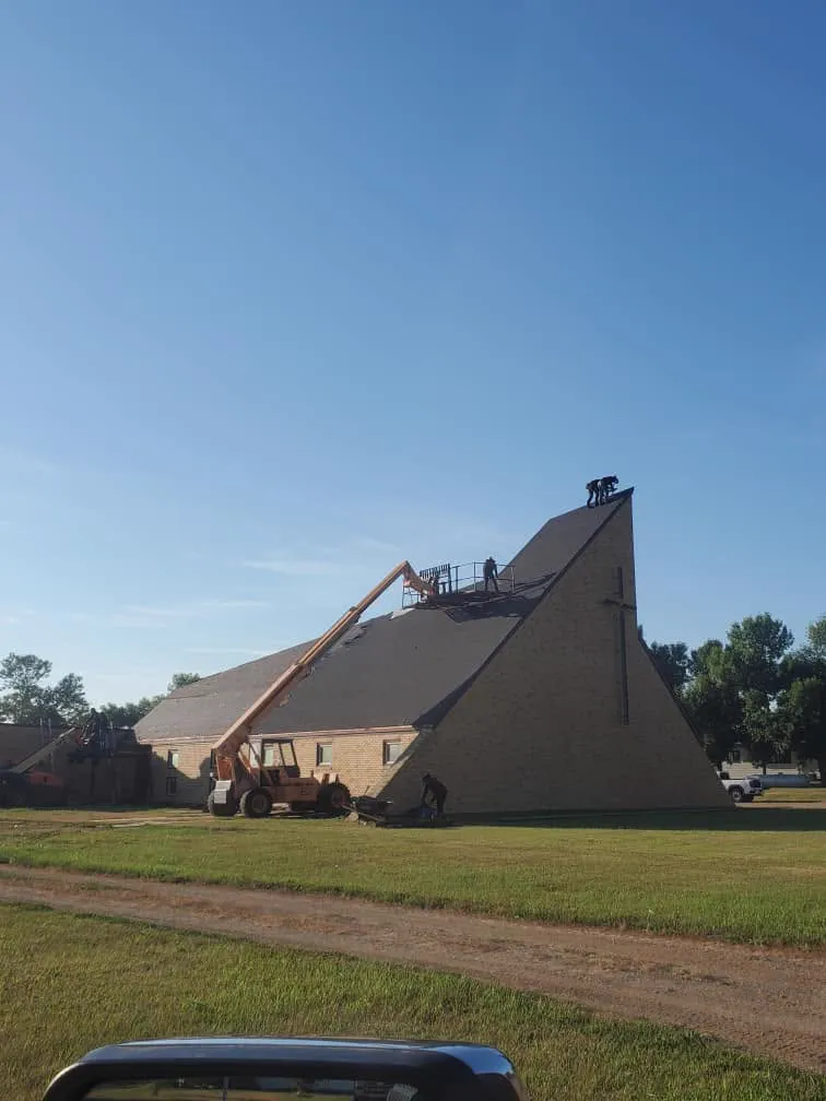 A boom lift reaching the steep roof of an A-frame church