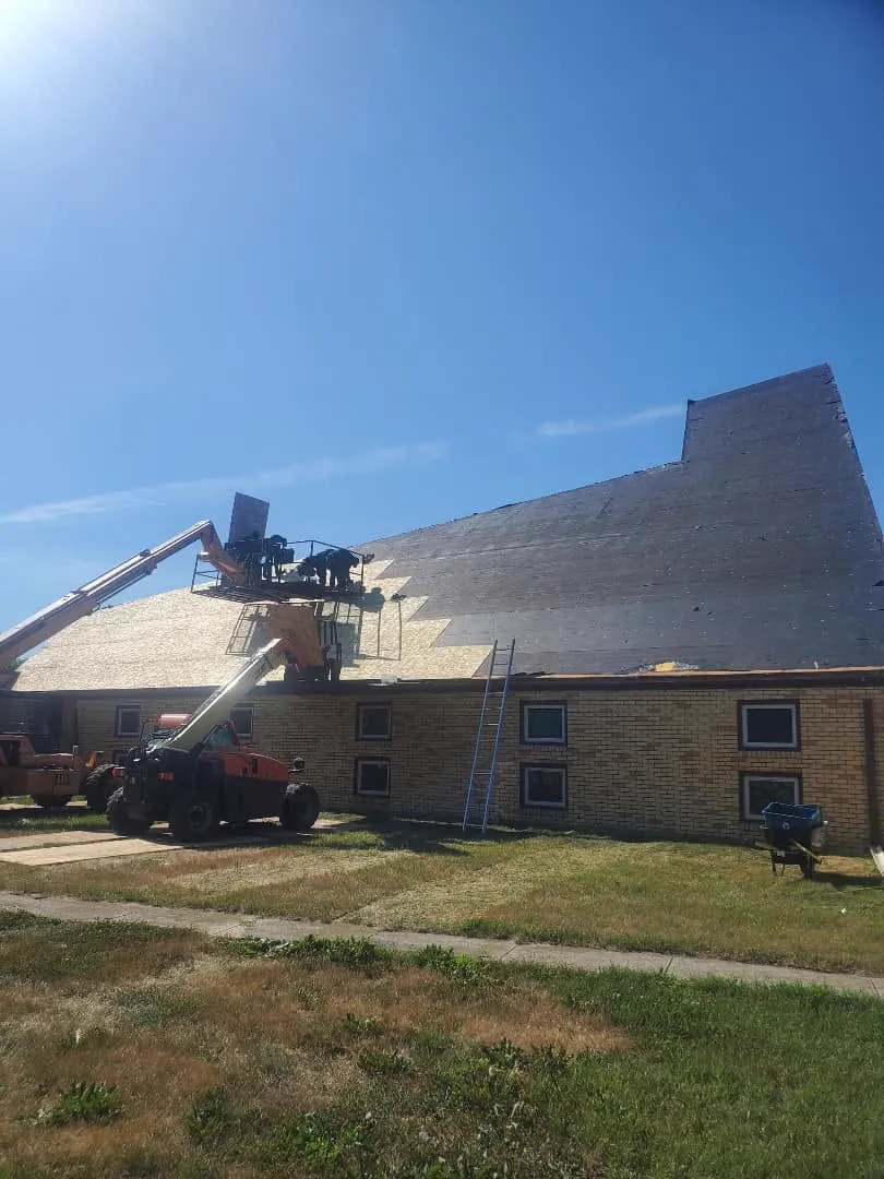 A boom lift and crew installing new decking on a commercial building