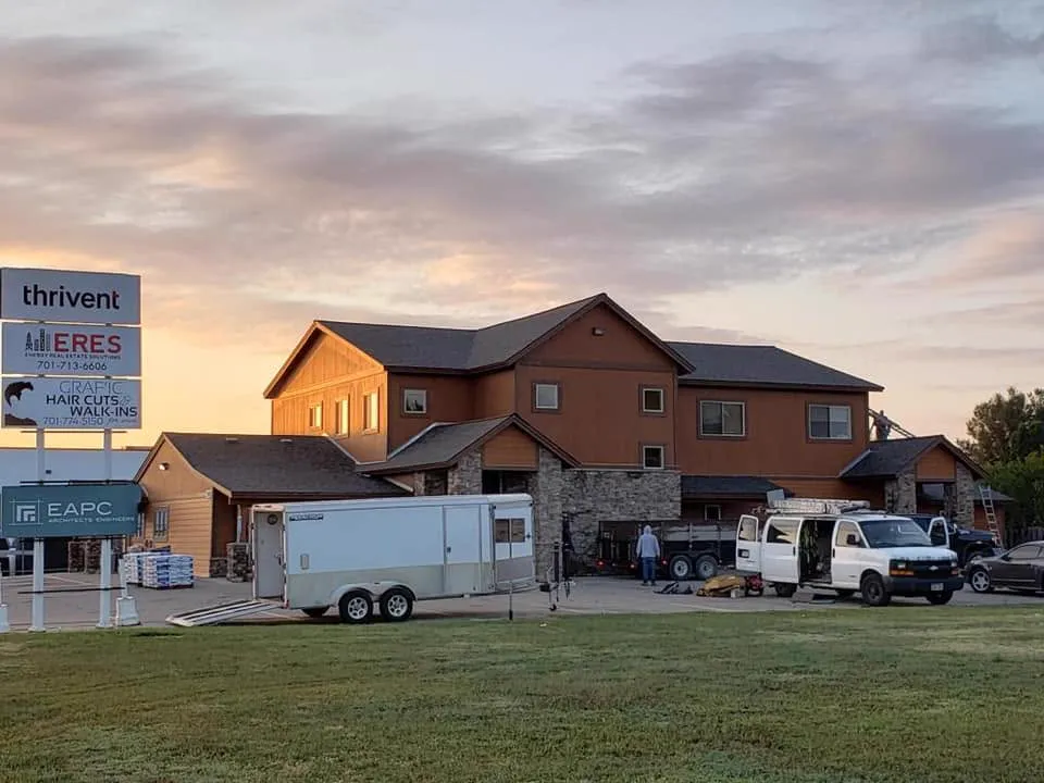 A Tops Roofing crew reroofing a commercial storefront at sunset
