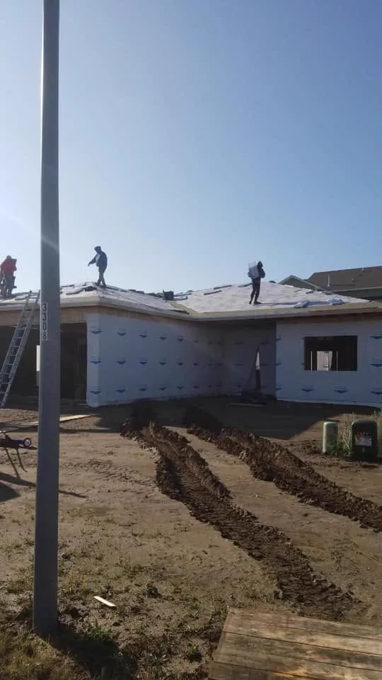 A crew installing underlayment on a new-construction home