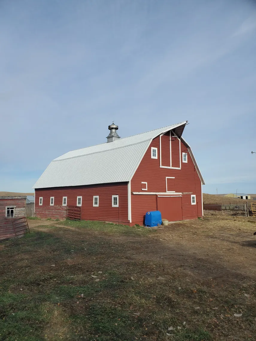 A red barn with a newly installed silver metal roof