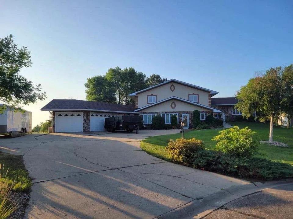 A finished asphalt-shingle roof on a two-story home with stone accents
