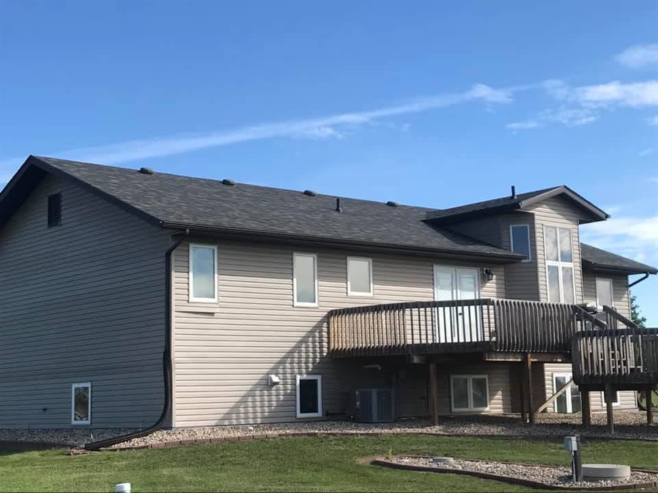 A finished asphalt-shingle roof on a two-story home with an attached deck